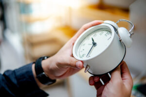 Male hand adjusting the time on white clock