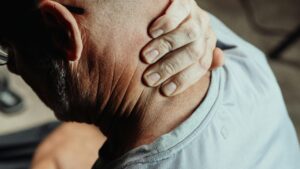 Photo of man holding his neck, who is injured